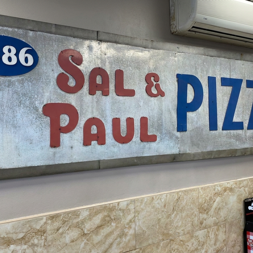 Vintage wall sign reading “1686 Sal & Paul Pizzeria” above a tiled restaurant wall.